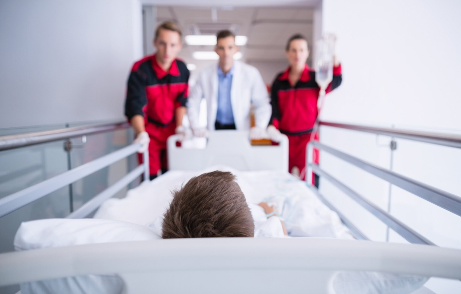 Paramédicos y doctor transportando a un paciente en una camilla dentro de un hospital